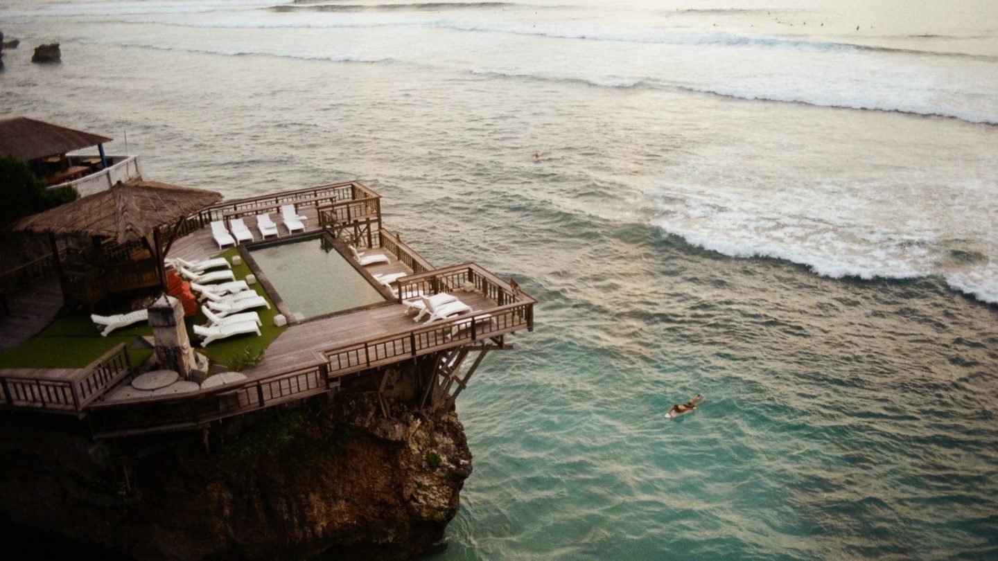 Aerial view of a clifftop villa pool and deck overlooking the ocean in Bali