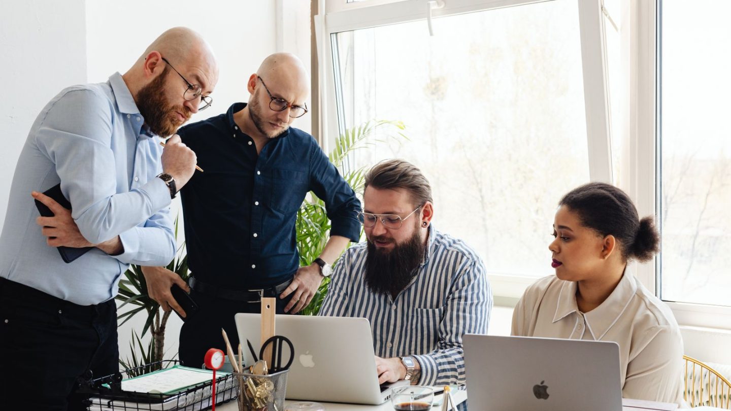 Small business team looking at laptops while reviewing a workflow