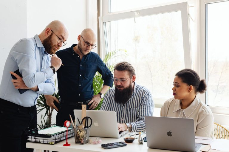 Small business team looking at laptops while reviewing a workflow