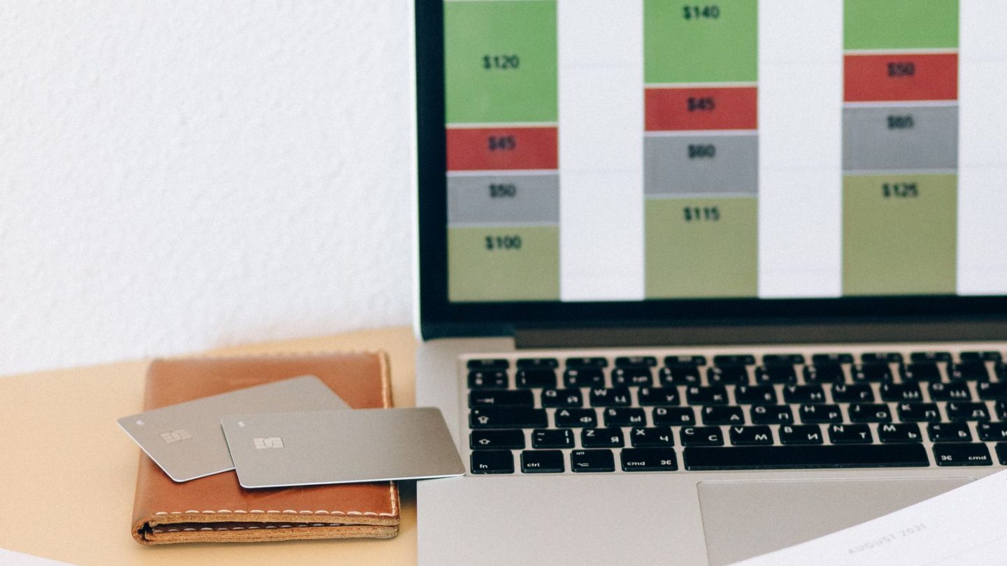 Laptop screen showing a website project cost breakdown next to budgeting documents