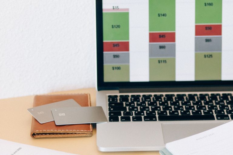 Laptop screen showing a website project cost breakdown next to budgeting documents