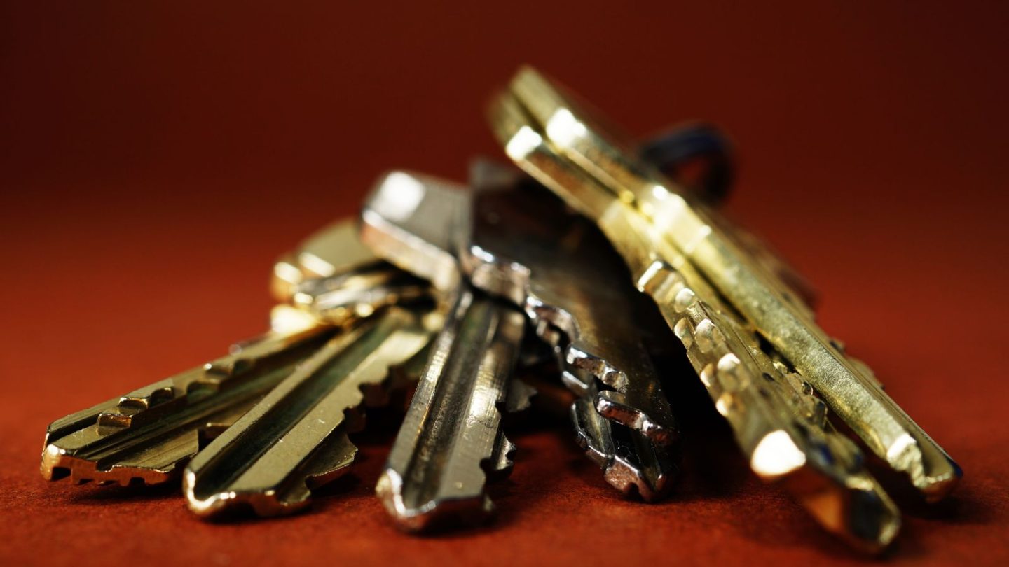 A bunch of brass keys on a dark red background