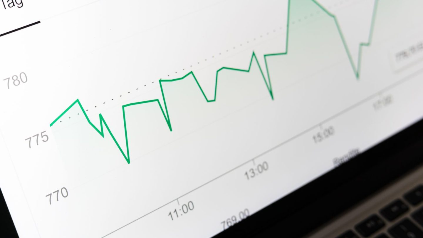 Laptop screen showing a green line chart of performance data
