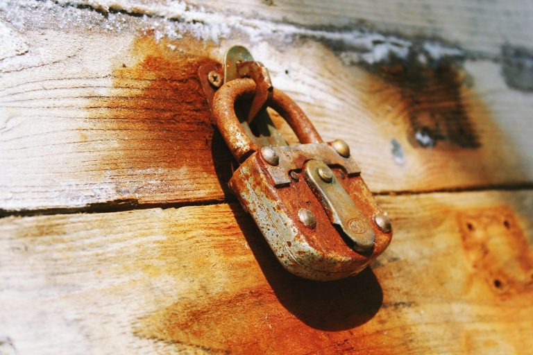 Old rusty padlock hanging on a weathered wooden door